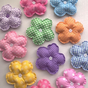 May include: Ten colorful fabric flower shapes with different patterns, including polka dots, gingham, and floral prints. Each flower has a button in the center.