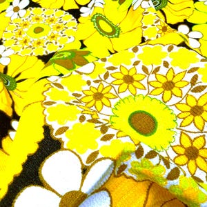 May include: Yellow and white floral fabric with a repeating pattern of stylized flowers. The fabric has a textured, almost fuzzy surface.
