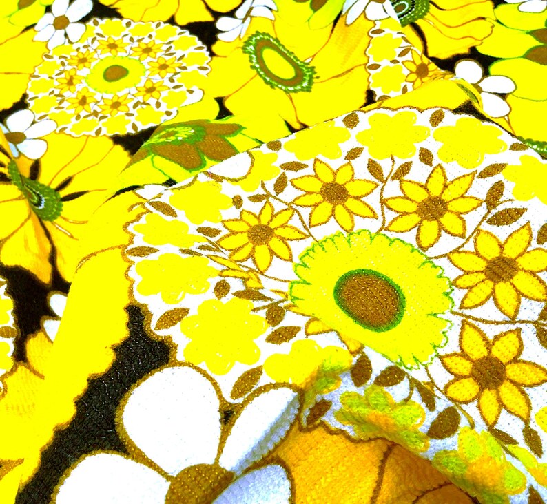 May include: Yellow and white floral fabric with a repeating pattern of stylized flowers. The fabric has a textured, almost fuzzy surface.