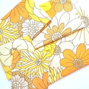 May include: A set of fabric scraps featuring a vintage floral pattern in shades of yellow, orange, and white. The fabric is perfect for quilting, crafting, or making home decor.