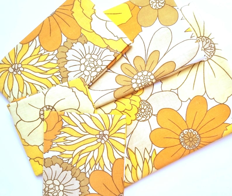 May include: A set of fabric scraps featuring a vintage floral pattern in shades of yellow, orange, and white. The fabric is perfect for quilting, crafting, or making home decor.
