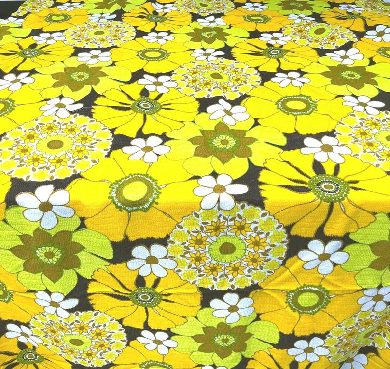 May include: Yellow and green floral fabric with a repeating pattern of large and small flowers. The fabric has a retro 1970s style.
