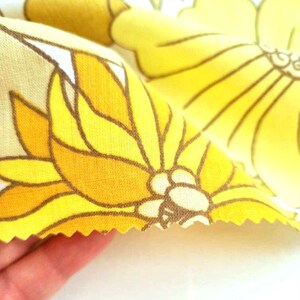 May include: Yellow and brown floral fabric with a white background. The fabric has a scalloped edge.