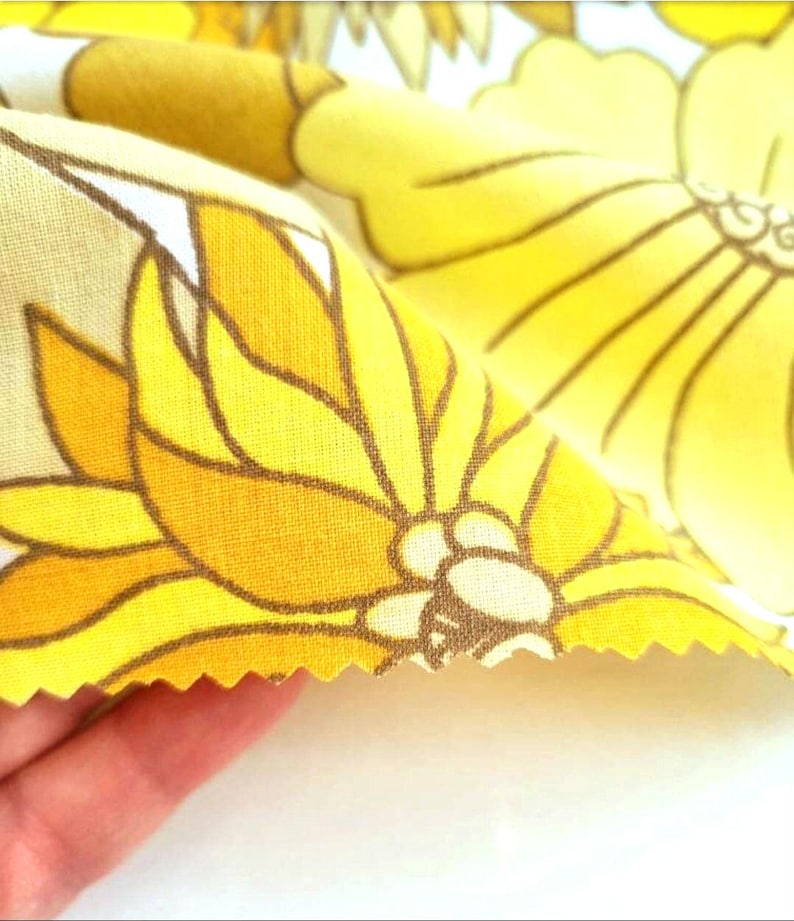 May include: Yellow and brown floral fabric with a white background. The fabric has a scalloped edge.