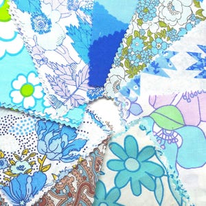 May include: A collection of fabric swatches arranged in a circular fan pattern. The squares feature various blue, white, and green prints, including floral, paisley, and geometric designs with pinked edges on several pieces of the cotton material.