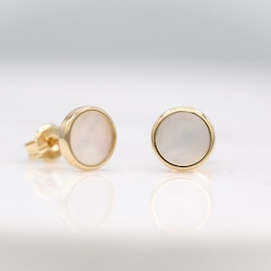 Puede incluir: Un par de pendientes de oro con piedras redondas de madreperla blanca.