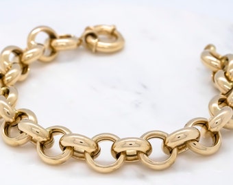 May include: A gold chain bracelet with large, round links. The bracelet is made of polished gold and has a simple, elegant design.