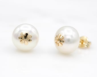 May include: A pair of white pearl earrings with a gold flower design.