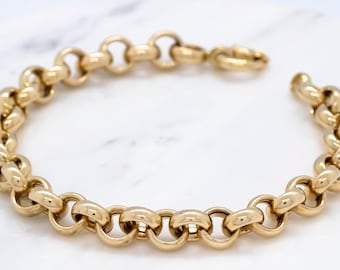 Op de afbeelding: Een gouden kettingarmband met een dik, afgerond schakeld ontwerp.