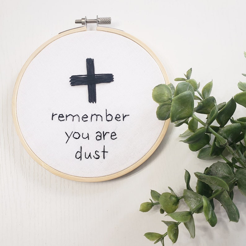 Remember you are dust hand embroidered on a white fabric, with black cross.