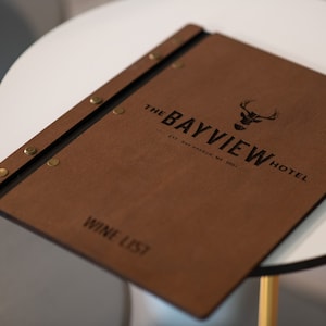 Elevate your brand with our Wooden Menu Holder featuring Logo Engraving. Personalize your presentation with ease using this handcrafted menu folder. Easily swap pages for a fresh, sophisticated look. Discover elegance with our Wooden Menu Cover.