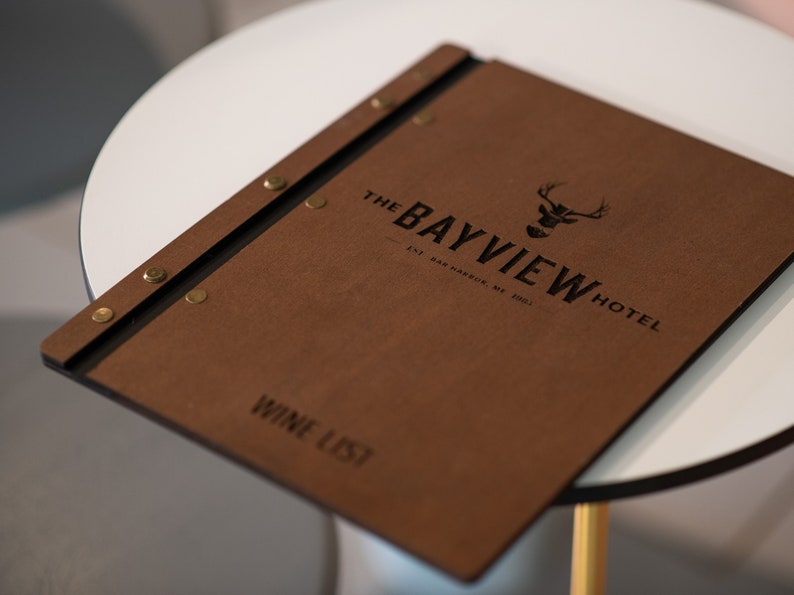 Elevate your brand with our Wooden Menu Holder featuring Logo Engraving. Personalize your presentation with ease using this handcrafted menu folder. Easily swap pages for a fresh, sophisticated look. Discover elegance with our Wooden Menu Cover.