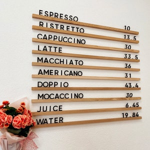 Enhance your café's ambiance with this elegant menu board, featuring sturdy oak rails and clear acrylic letters, offering a modern and inviting presentation of your establishment's menu options for customers to peruse.