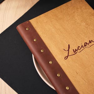 logo laser engraved on a plywood surface — close-up of the script version. The cursive font is clear and well-reproduced on the plywood. Script logos require good engraving resolution to render cleanly — thin strokes and curved lines can become indistinct if the laser settings aren't calibrated correctly for the specific plywood surface. This shot confirms the script engraving is clean and legible, which is important for buyers who want a typographic logo rather than an illustrated one.