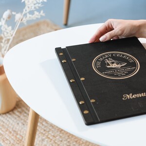 Elevate your brand with our Wooden Menu Holder featuring Logo Engraving. Personalize your presentation with ease using this handcrafted menu folder. Easily swap pages for a fresh, sophisticated look. Discover elegance with our Wooden Menu Cover.