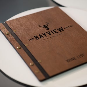 Elevate your brand with our Wooden Menu Holder featuring Logo Engraving. Personalize your presentation with ease using this handcrafted menu folder. Easily swap pages for a fresh, sophisticated look. Discover elegance with our Wooden Menu Cover.