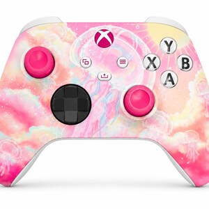 May include: A wireless video game controller featuring a pink and yellow gradient design with jellyfish illustrations, clouds, and stars. The controller includes two bright pink joysticks, a black directional pad, and white buttons labelled Y, X, B, and A.