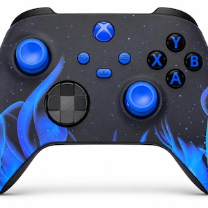 May include: A wireless video game controller featuring a matte black base with a vibrant blue flame pattern across the grips. It includes two bright blue analogue sticks, a black directional pad, and standard action buttons labelled A, B, X, and Y.