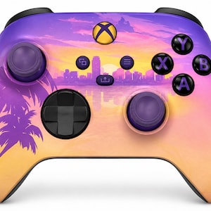 May include: A wireless video game controller featuring a sunset gradient design with purple palm tree silhouettes on the left side and a city skyline graphic in the centre. The device includes black analogue sticks, a black D-pad, and labelled buttons.