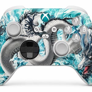 May include: A wireless video game controller featuring a white and teal graphic print of a long, winding dragon surrounded by swirling water patterns. The controller includes a black directional pad, two light grey joysticks, and white action buttons.