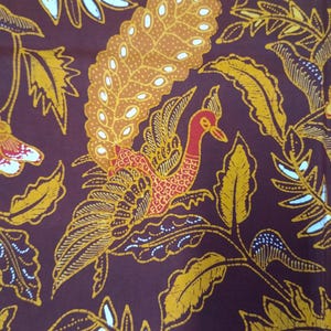 Könnte beinhalten: Nahaufnahme eines Stoffes mit einem sich wiederholenden Muster aus Vogel und Blättern. Der Vogel ist rot und orange mit einem langen Schwanz. Die Blätter sind gelb und weiß auf einem dunkelbraunen Hintergrund.