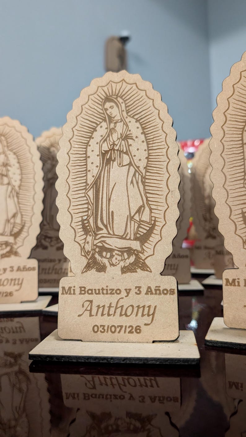 Pode incluir: Um suporte de madeira castanho-claro cortado a laser com uma imagem gravada da Virgem de Guadalupe. A base inclui o texto Mi Bautizo y 3 A&ntilde;os, o nome Anthony e a data 03/07/26. A pe&ccedil;a tem uma borda recortada e mant&eacute;m-se na vertical.