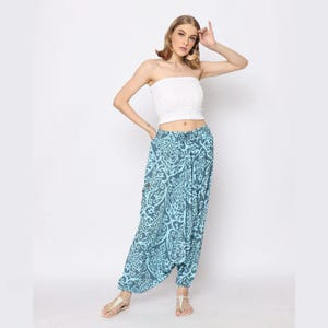 May include: A woman wearing a white tube top and blue printed pants with a drawstring waist. The pants have a loose, flowing fit and a wide leg.