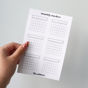 Op de afbeelding: Een printbaar vel met zes lege maandelijkse trackers. Elke tracker heeft ruimte voor een maandnaam en een raster met 30 vierkanten.