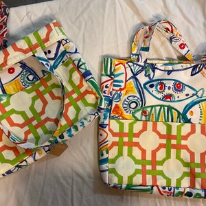 May include: Two colorful tote bags with a geometric pattern and a design of colorful fish. The bags have a white background with green, orange, and blue accents.