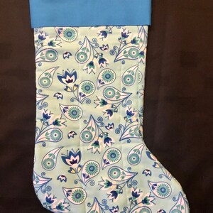 May include: A blue and white Christmas stocking with a paisley pattern. The stocking has a blue cuff and a loop at the top.
