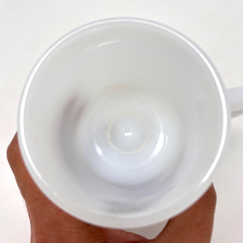 May include: A white ceramic mug with a smooth, glossy finish. The inside of the mug is clean and free of any stains.