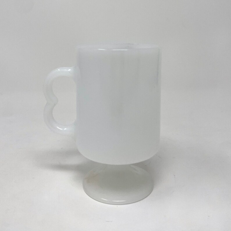 May include: White ceramic mug with a heart-shaped handle and a pedestal base.