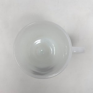 May include: White ceramic coffee mug with a rounded handle. The mug is empty and has a smooth, glossy finish.
