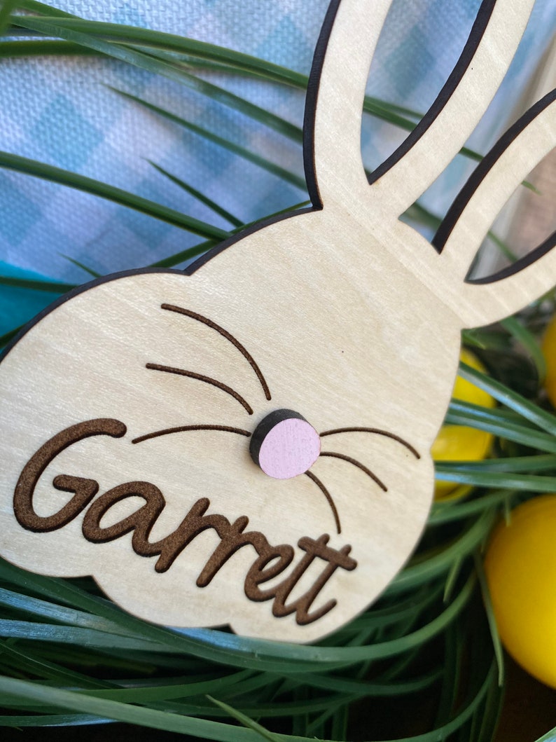 Puede incluir: Decoraci&oacute;n de Pascua de conejo de madera con una nariz rosa y el nombre "Garrett" grabado en ella.