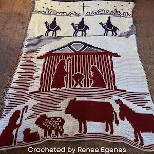 May include: A handmade, white and burgundy crochet blanket featuring a nativity scene. The blanket depicts the three wise men on camels, a stable with Mary, Joseph, and baby Jesus, and various animals. The text "Crocheted by Renee Egenes" is at the bottom.