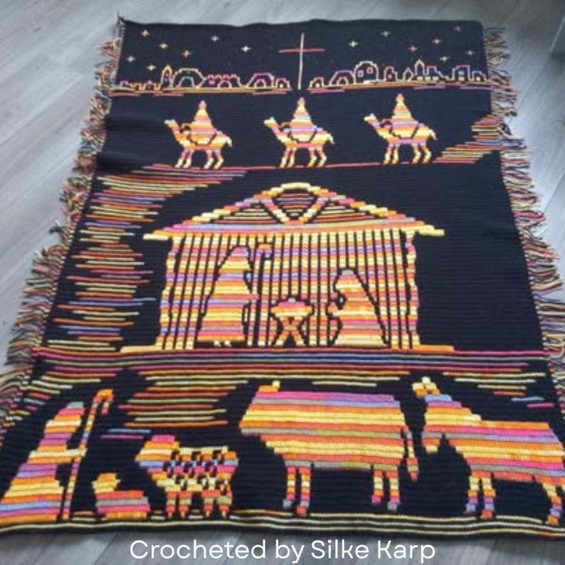 May include: Black crocheted blanket featuring a nativity scene with camels, a stable, and various animals. The blanket has a fringed edge and the text "Crocheted by Silke Karp" at the bottom.