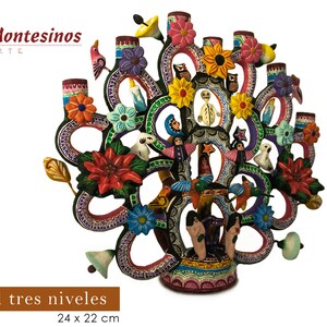 Pu&ograve; includere: Un albero decorativo a tre livelli, dipinto a mano con motivi floreali e di uccelli. L'albero misura circa 24 x 22 cm. L'immagine include il testo "Montesinos Arte" e "&Aacute;rbol tres niveles".