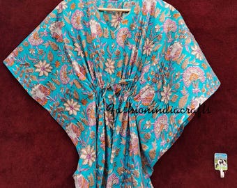 May include: A turquoise blue cotton kaftan with a floral print. The kaftan has a V-neck and a tie at the waist. The fabric is soft and flowy. The kaftan is perfect for a relaxed and comfortable look.