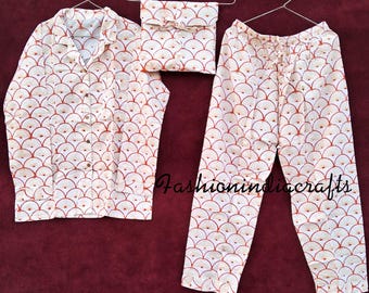 May include: White pajamas with a red and white geometric pattern. The pajamas include a long-sleeved shirt with a button-up front and matching pants.