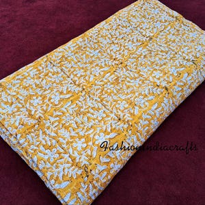 Puede incluir: Una colcha kantha amarilla y blanca con un patr&oacute;n floral. La colcha est&aacute; hecha de algod&oacute;n y est&aacute; cosida a mano. Es un textil indio tradicional.