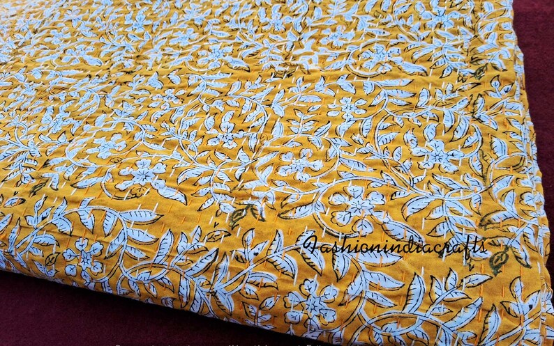 Puede incluir: Una colcha kantha amarilla y blanca con un patr&oacute;n floral. La colcha est&aacute; hecha de algod&oacute;n y est&aacute; cosida a mano. La colcha es perfecta para a&ntilde;adir un toque de estilo bohemio a tu hogar.