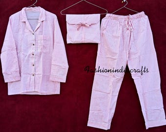 May include: A pink and white striped pajama set, including a button-down shirt, drawstring pants, and a matching pouch. The shirt has a chest pocket. The text "fashionindicrafts" is visible on the bottom of the image.