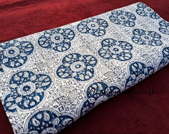 Puede incluir: Tela blanca con un patrón floral azul y blanco. La tela tiene un patrón repetitivo de flores grandes y estilizadas con detalles intrincados.