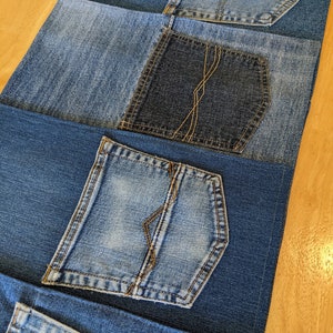 May include: Four pieces of blue denim fabric with different sized pockets sewn on. The pockets are all different shades of blue denim.