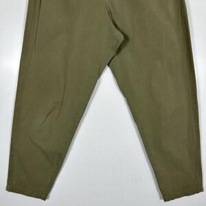 Puede incluir: Pantalones verde oliva con cintura el&aacute;stica y cierre de bot&oacute;n. Los pantalones tienen un corte relajado y un aspecto ligeramente descolorido. La tela parece ser una mezcla de algod&oacute;n duradera.