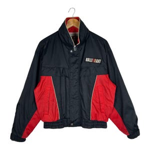 May include: A black and red jacket featuring a high collar, a front zipper closure, and a RALLIART patch on the chest. The design includes long sleeves with red panels, a ribbed hem, and a red interior lining visible at the neck area.