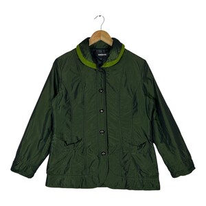 May include: A dark olive green quilted jacket featuring a contrasting lime green collar, a front button closure with dark circular buttons, and two front pockets. The jacket has long sleeves and a smooth, slightly reflective synthetic fabric finish.