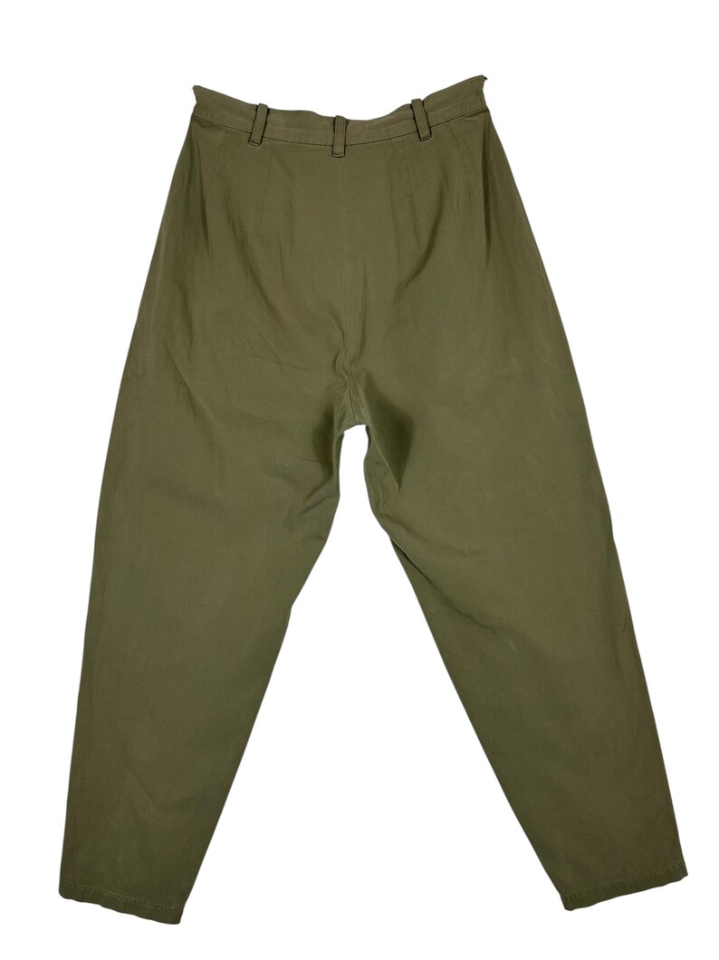 Puede incluir: Pantalones verde oliva con cintura alta y corte relajado. Los pantalones tienen trabillas y cierre de bot&oacute;n. La tela parece ser un material ligero, adecuado para ropa informal. Los pantalones est&aacute;n colocados planos sobre un fondo blanco.