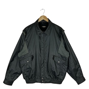 May include: A black bomber jacket with a collared neckline and two front pockets. The jacket has a ribbed hem and cuffs, and a gray patch on the shoulders. The jacket is hanging on a wooden hanger.