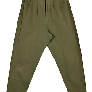 Puede incluir: Pantalones plisados ​​verde oliva con cierre de bot&oacute;n y cremallera. Los pantalones tienen un corte holgado y una cintura alta. La tela parece ser un algod&oacute;n ligero o una mezcla. Los pantalones son de color liso y tienen un estilo cl&aacute;sico y vintage.